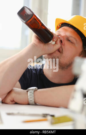 Arm of drunken worker in yellow helmet Stock Photo