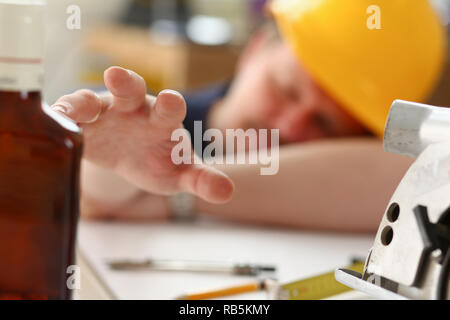 Arm of drunken worker in yellow helmet Stock Photo