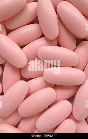 Vertical image of pile of pastel pink oval shaped pills for background or banner Stock Photo