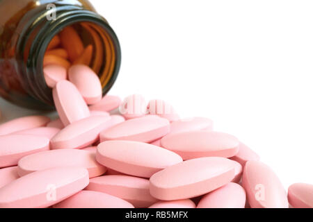Heap of pastel pink oval shaped pills scattered from smoky brown glass bottle on white background Stock Photo