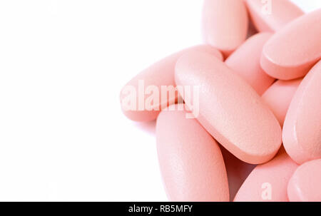 Macro shot of pastel pink oval shaped pills on white background with free space for text and design Stock Photo