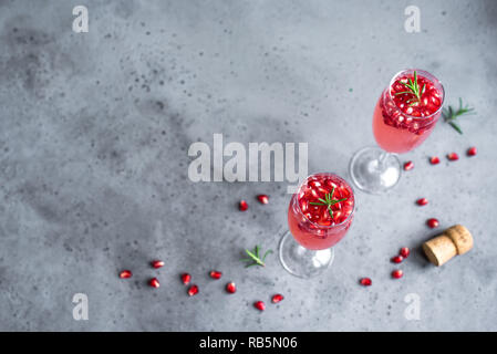 Pomegranate Champagne Mimosa Cocktail (Mocktail) with rosemary on concrete background, copy space. Mimosa Drink for Valentine Day or other holidays. Stock Photo