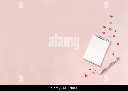 Notebook and pen with red hearts, stars on pink background, copy space. Minimal flat lay with planning on pink desk for Valentine day, love and romanc Stock Photo