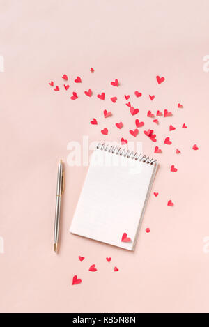 Notebook and red hearts isolated on beige background, copy space. Minimal flat lay with planning for Valentine day, love and romance concept, top view