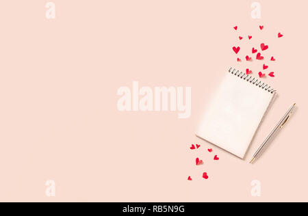 Notebook and red hearts isolated on beige background, copy space. Minimal flat lay with planning for Valentine day, love and romance concept, top view Stock Photo