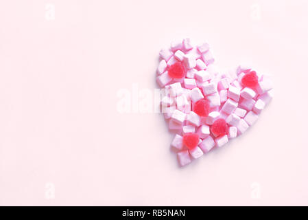 Pink marshmallow and candies in the shape of heart on pink background, copy space. Sweet pink pastel heart as minimal mock up, love and Valentine Day  Stock Photo