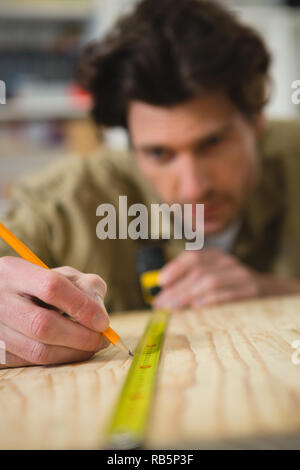 Male carpenter measuring and marking wood Stock Photo