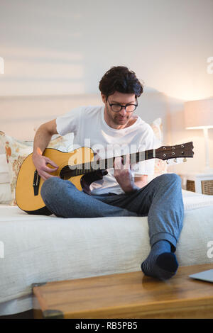 Man playing guitar in bedroom Stock Photo