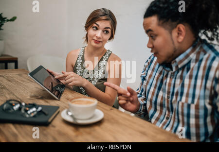 Two young creatives looking serious while pointing at a tablet ina boardroom Stock Photo