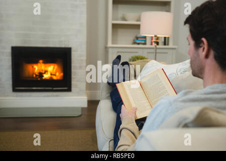 Man reading a book in living room Stock Photo