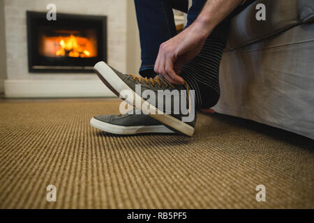 Man tying shoelaces in living room at home Stock Photo