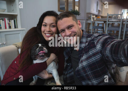 Couple having fun with their pet dog in living room Stock Photo