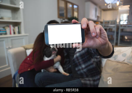 Couple taking selfie with mobile phone in living room Stock Photo
