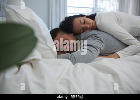 Couple sleeping on bed in bedroom Stock Photo