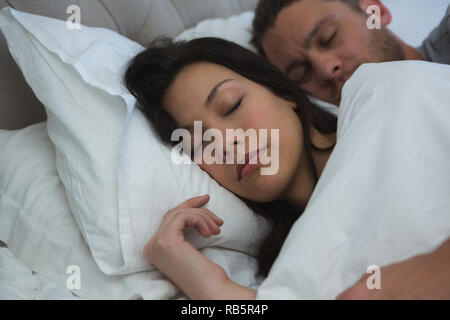 Couple sleeping on bed in bedroom Stock Photo
