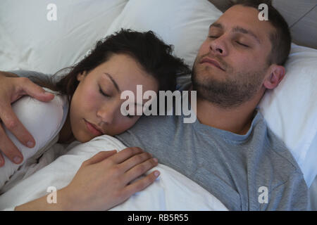 Couple sleeping on bed in bedroom Stock Photo