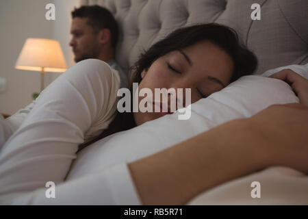 Woman sleeping while man working in bedroom
