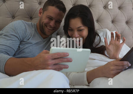 Couple using digital tablet in bedroom Stock Photo