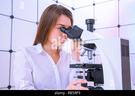 Scientist analyzing microscope slide at laboratory. Young woman technician is examining a histological sample, a biopsy in the laboratory of cancer re Stock Photo