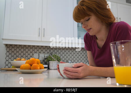 Woman having breakfast in kitchen Stock Photo