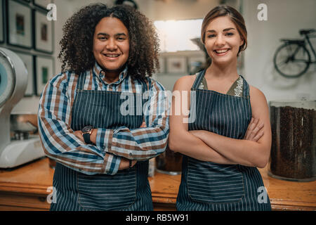 Portrait of two smiling baristas with arms crossed at the coffee shop Stock Photo