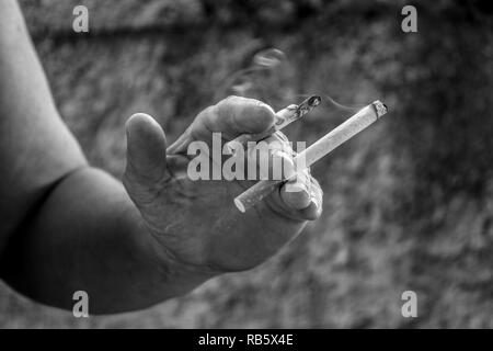 Human hand holding two cigarettes burning at the same time Stock Photo