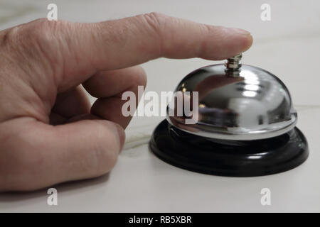 Person rings a table bell at the hotel reception desk Stock Photo