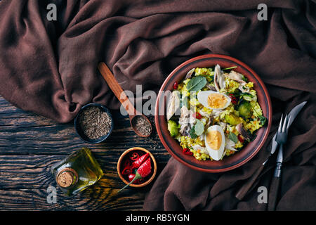 delicious Kedgeree with flaked smoked fish, hard boiled eggs, rice, kale, brussel sprouts, spices and herbs in a bowl on an old wooden table with fenn Stock Photo