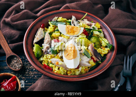 Kedgeree with flaked smoked fish, hard boiled eggs, rice, kale, brussel sprouts, spices and herbs in a bowl on an old wooden table with fennel seeds,  Stock Photo