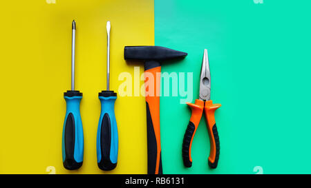 Tools worker, hammer, screwdrivers, pliers on bright yellow and blue background Stock Photo
