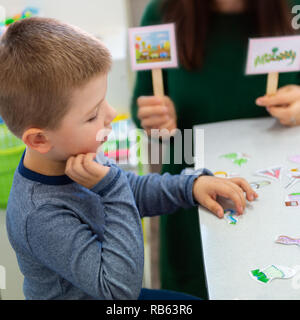 Young boy in speech therapy office. Preschooler exercising correct pronunciation with speech therapist. Child Occupational Therapy Session. Stock Photo
