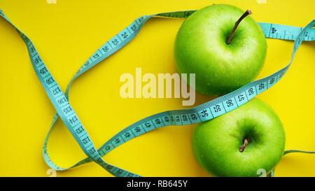 Green apples with measurements isolated on a yellow background. fitness food Stock Photo