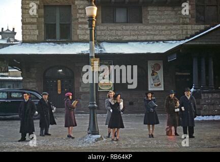 Colour photograph of commuters, who have just come off the train, waiting for the bus to go home, Lowell, Massachusetts, USA. Dated 1941 Stock Photo