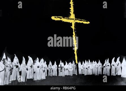 Photograph shows a group of Ku Klux Klan members with cross burning before them. Dated 1948 Stock Photo