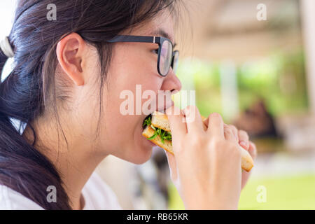 Yound female teenager eating her sandwich and pizza for lunch at restaurant Stock Photo