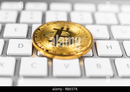 Bitcoin coin lying on white computer keyboard Stock Photo