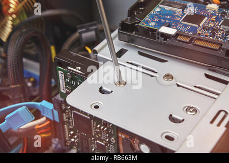 Hardware installation and upgrades of the unassembled computer system unit with help of screwdriver, close-up. Stock Photo