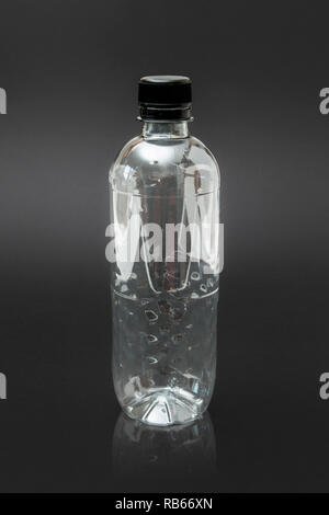 An empty generic single use plastic water bottle on a black background, no label Stock Photo