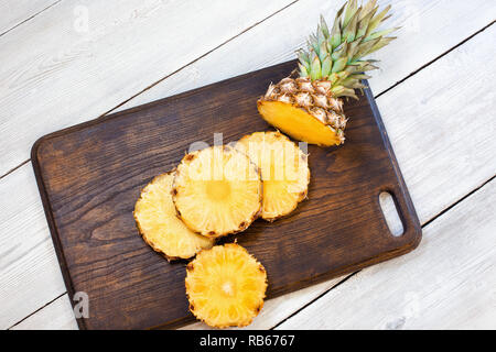 Sliced pineapple on brown and white wooden table. Center Stock Photo