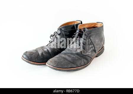 A pair of old tattered black leather lace-up shoes with water stains Stock Photo