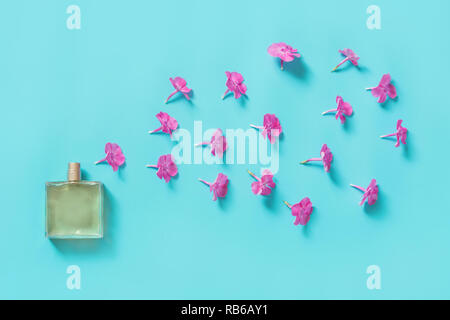 Creative still life. Perfume and blooming flowers of pink on blue. Concept spread of fragrance. View from above Stock Photo