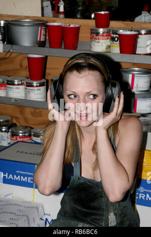 Blonde  Woman  wearing a protective apron while working in the print shop and listening to music with her headphones Stock Photo