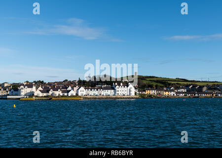The colorful waterfront of  Portaferry with a hill and green fields above the village along Strangford Lough in County Down, Northern Ireland Stock Photo