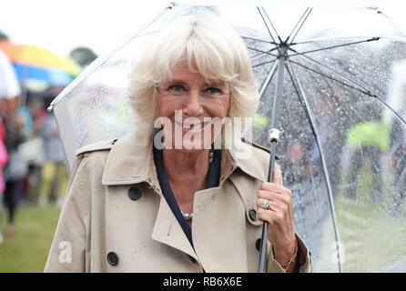 A Police Officer carries flowers and gifts as The Prince of Wales and The Duchess of Cornwall attend The Sandringham Flower Show held on the royal est Stock Photo