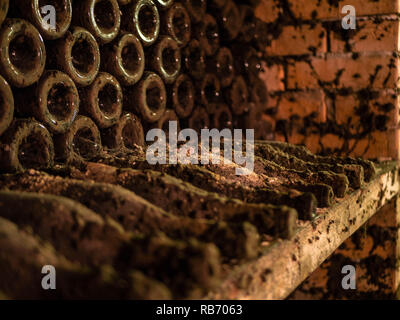 Very old wine bottles stocked in an ancient wine cellar Stock Photo