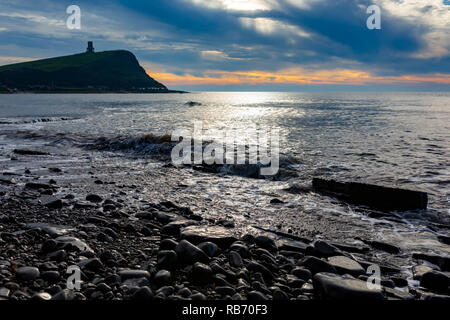 Landscape photograph on Kimmeridge bay beach over wavey water looking out onto Clavell tower under moody skies. Stock Photo