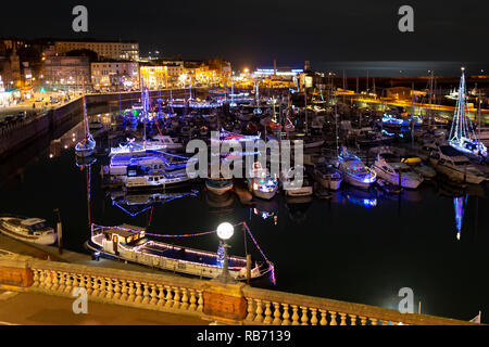 Landscape photograph of the christmas lights and decorations adorned on the boats within Ramsgate Royal harbour. Stock Photo