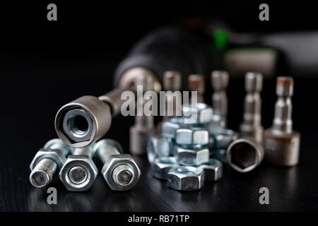 Screws, nuts and keys on a workshop table. Tools and accessories for mechanics. Black background. Stock Photo