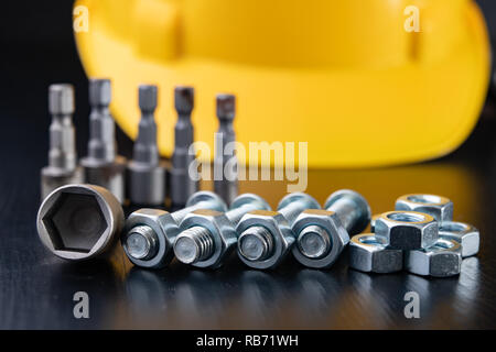 Screws, nuts and keys on a workshop table. Tools and accessories for mechanics. Black background. Stock Photo