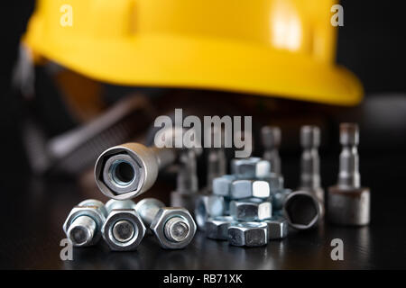 Screws, nuts and keys on a workshop table. Tools and accessories for mechanics. Black background. Stock Photo